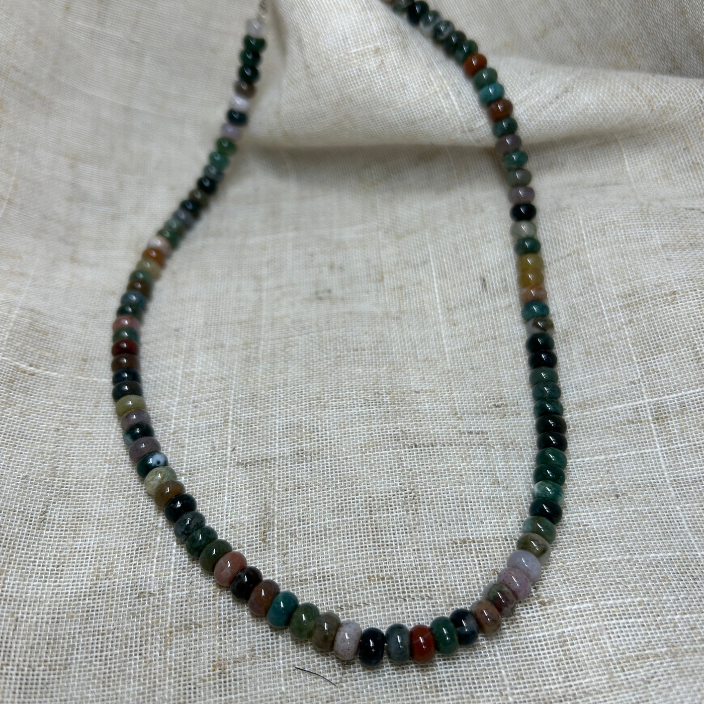 Necklace with multicolored beads on a textured fabric background