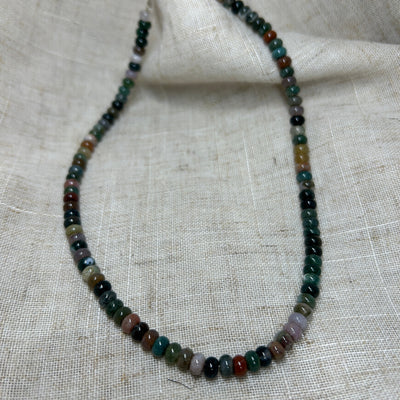 Necklace with multicolored beads on a textured fabric background