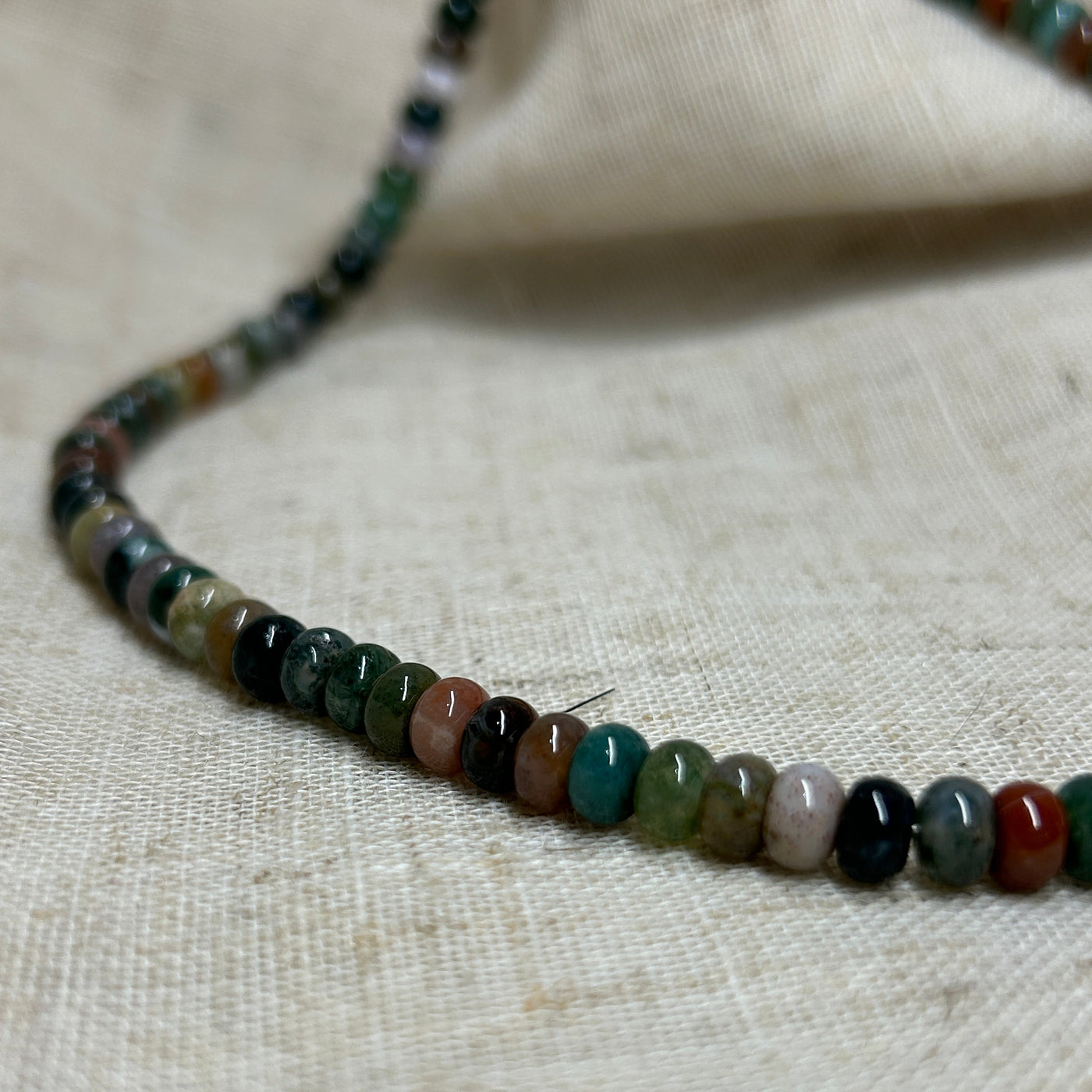 Necklace with multicolored beads on a textured beige background