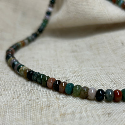 Necklace with multicolored beads on a textured beige background
