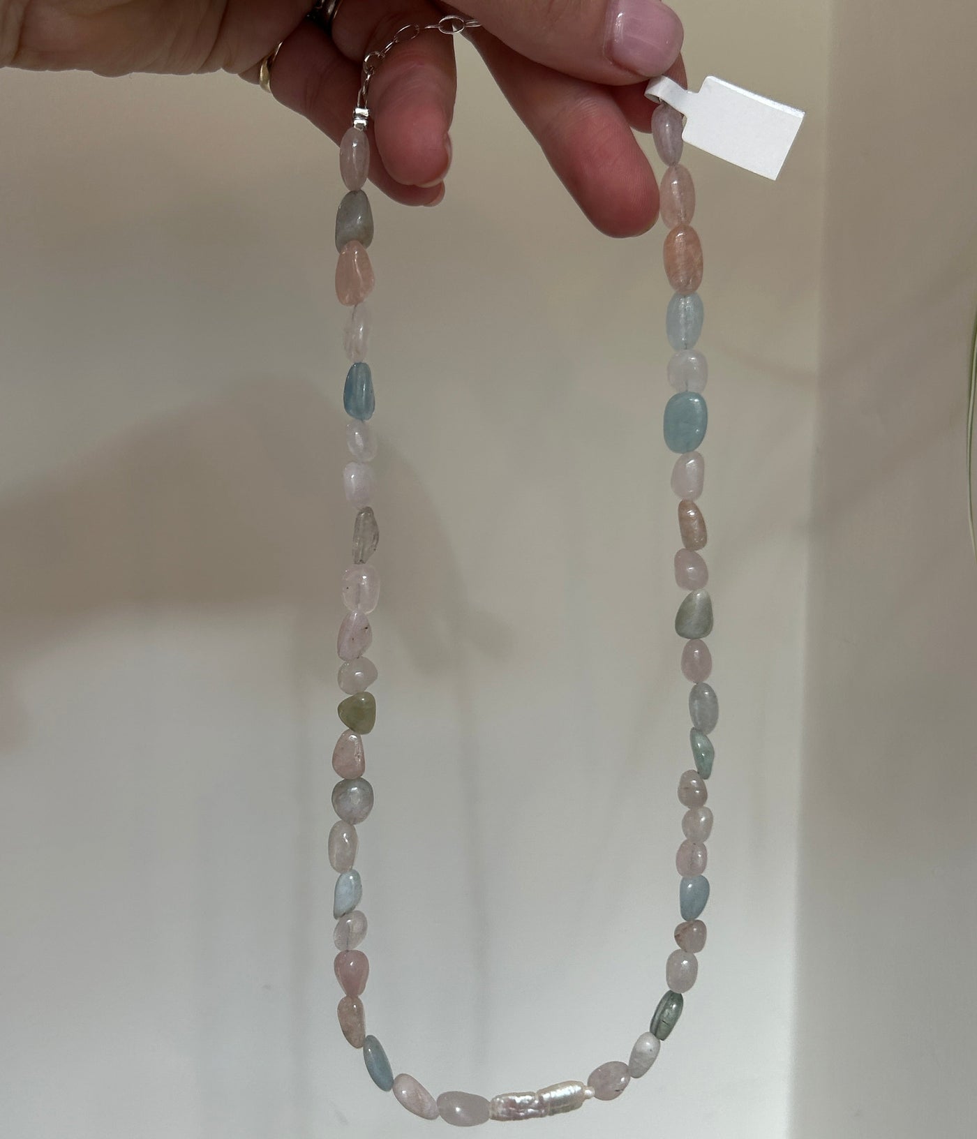 Beaded necklace held by a hand on a plain background