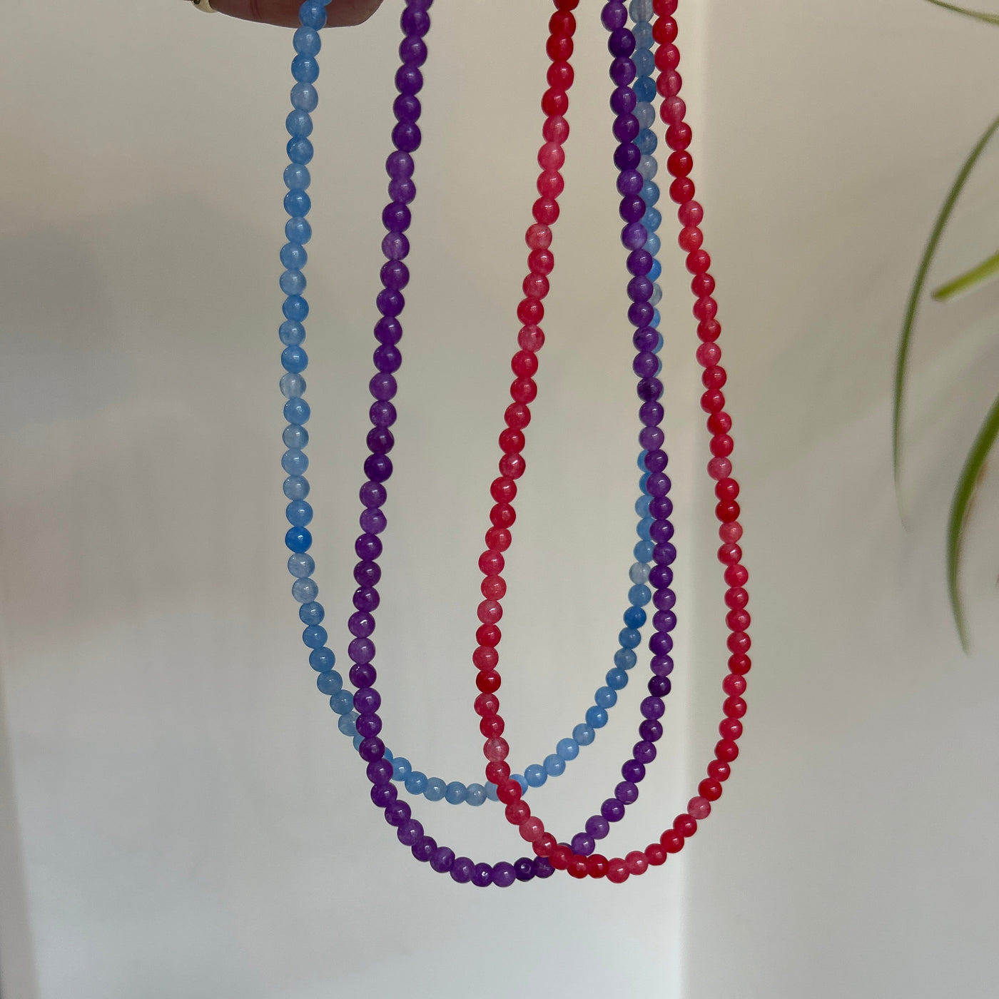 Three beaded strings in red, blue, and purple on a white background