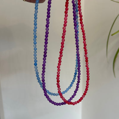 Three beaded strings in red, blue, and purple on a white background