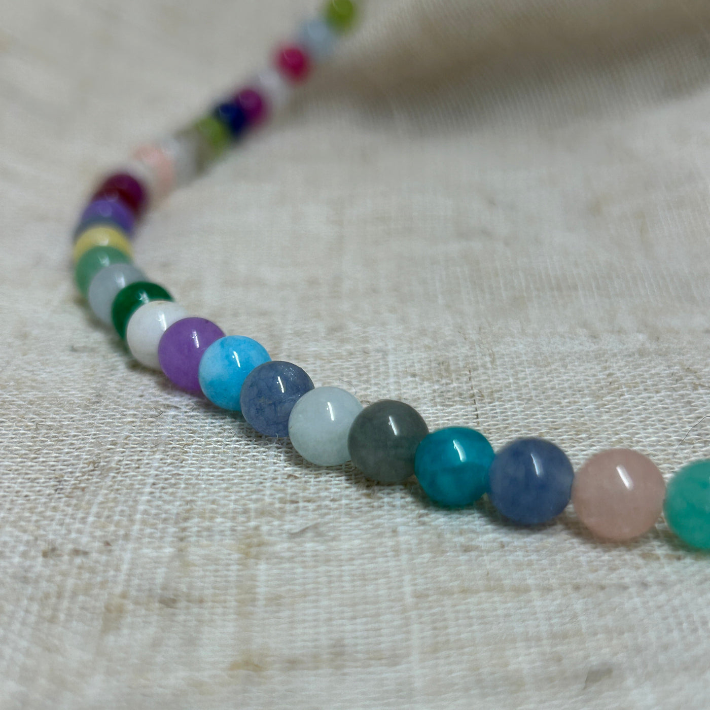 Necklace with multicolored beads on a textured fabric background