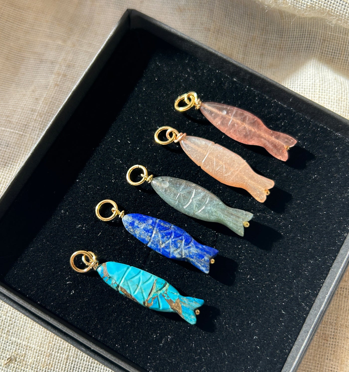 Five colorful fish-shaped charms on a black display stand.