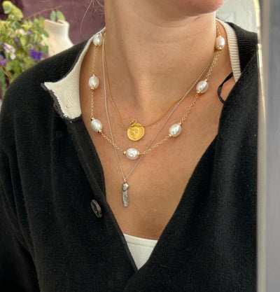 Close-up of a person wearing multiple pearl necklaces with a blurred background