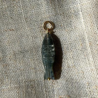 Small fish-shaped pendant on a textured fabric background