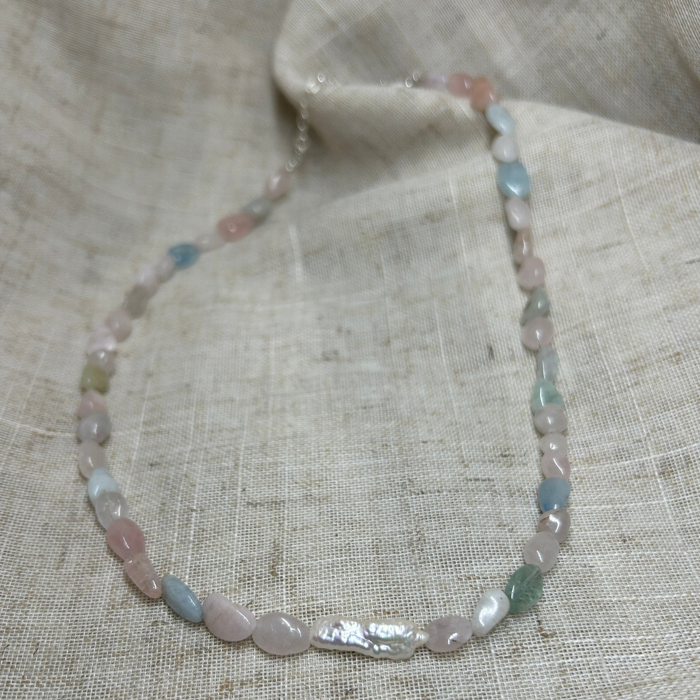 Necklace with multicolored beads on a textured fabric background