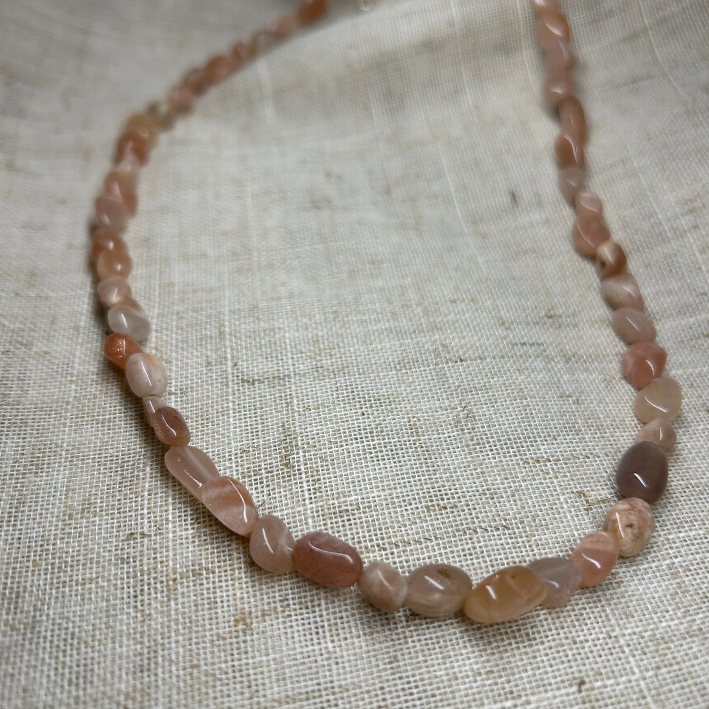 Necklace with pink and brown beads on a textured fabric background