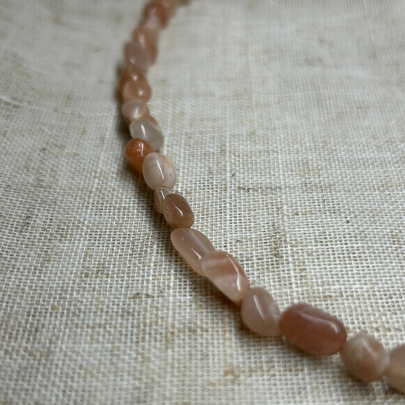 Necklace with pink beads on a textured beige fabric background