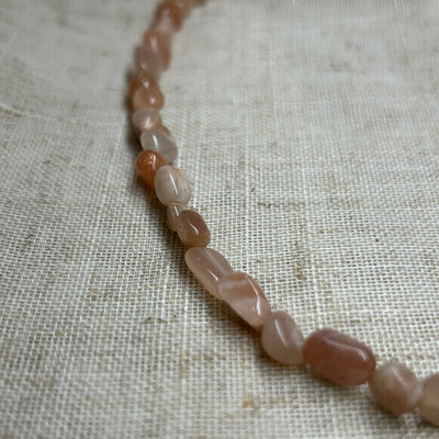 Necklace with pink beads on a textured beige fabric background