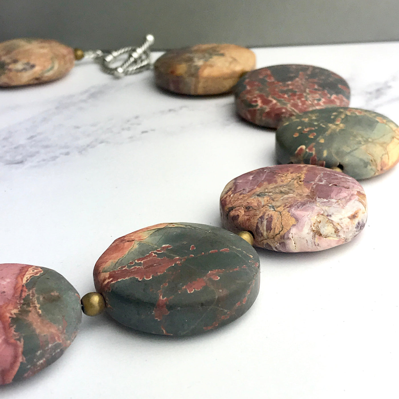 Necklace with marbled stone beads on a white surface