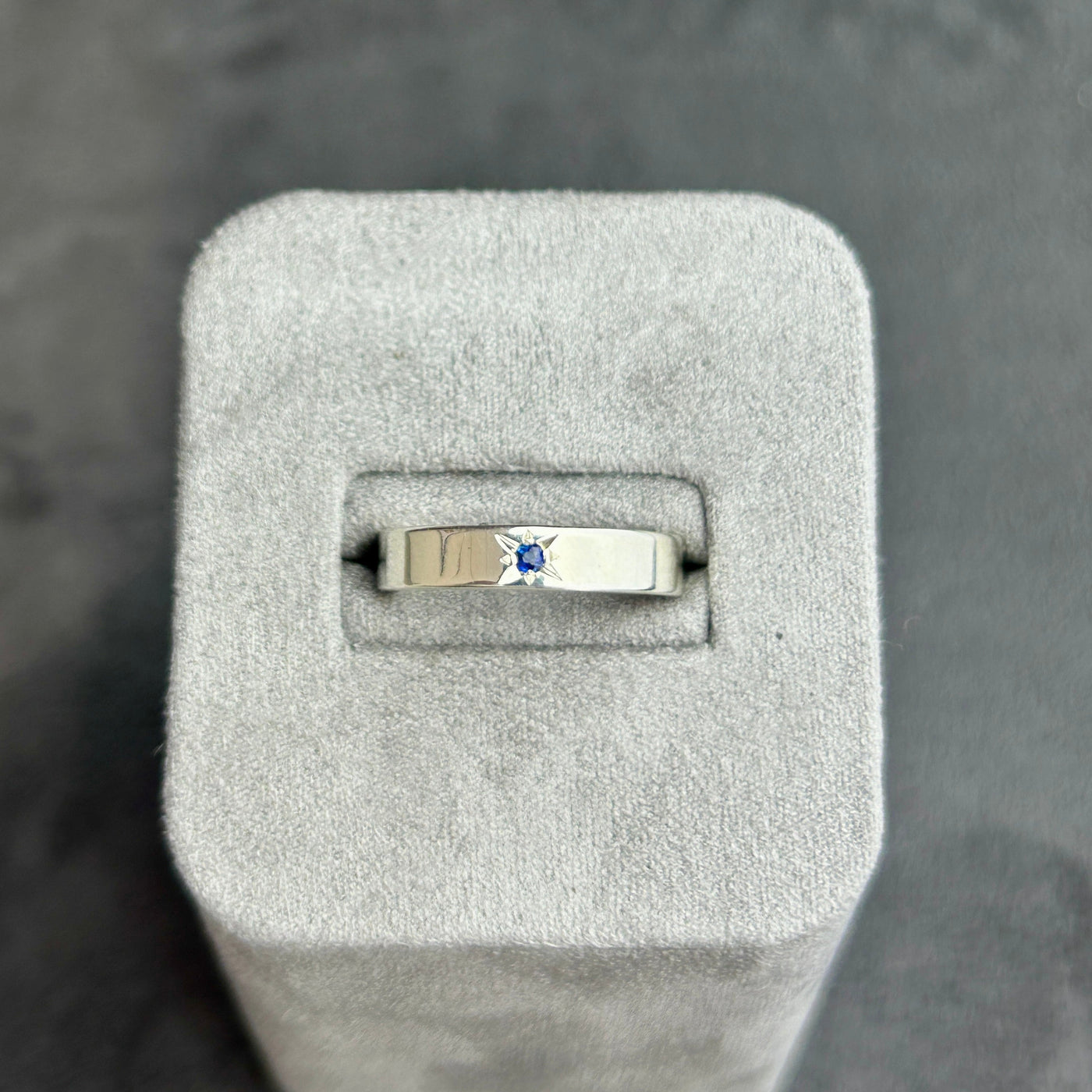 Sapphire ring in a grey jewelry box on a dark background