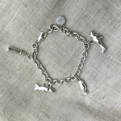 Silver Northumberland coastal charm bracelet on a textured fabric background