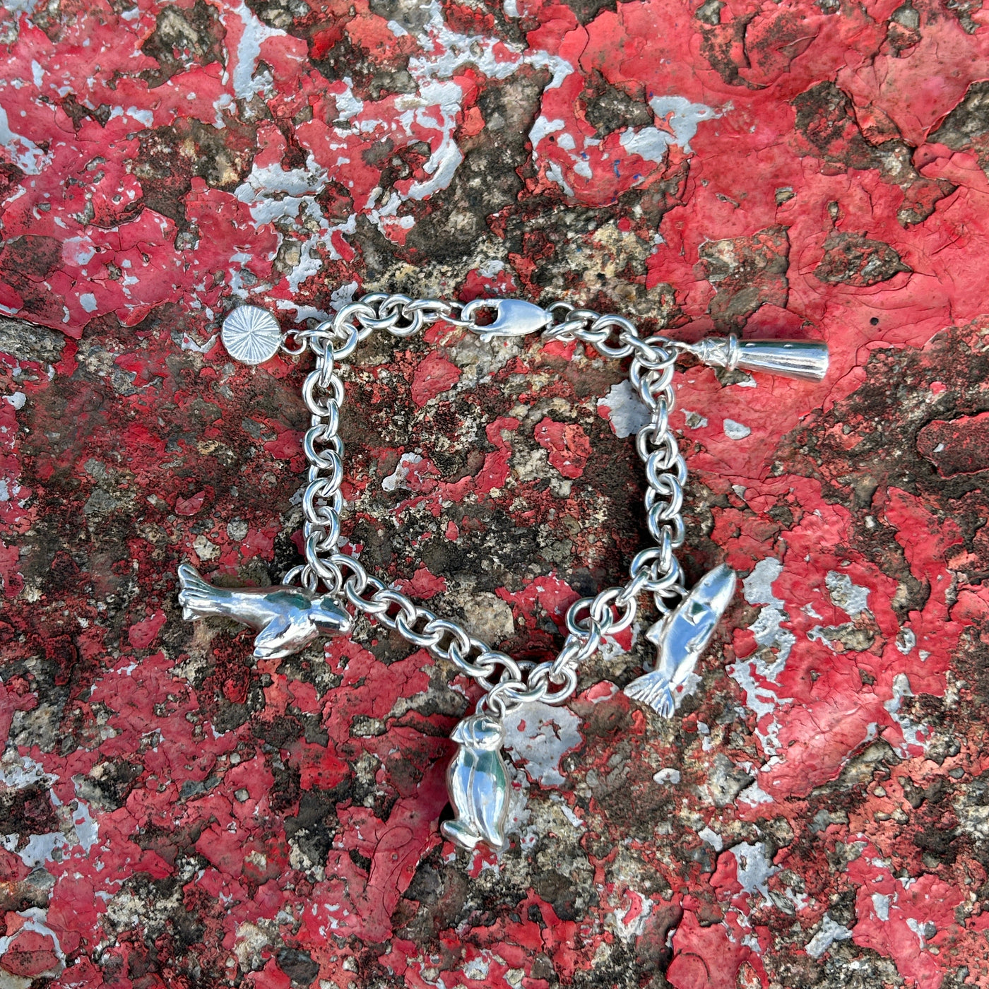 Silver bracelet with charms on a textured red and brown surface