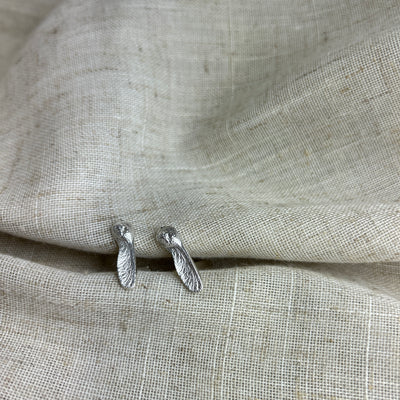 Silver sycamore cufflinks on a textured beige fabric background