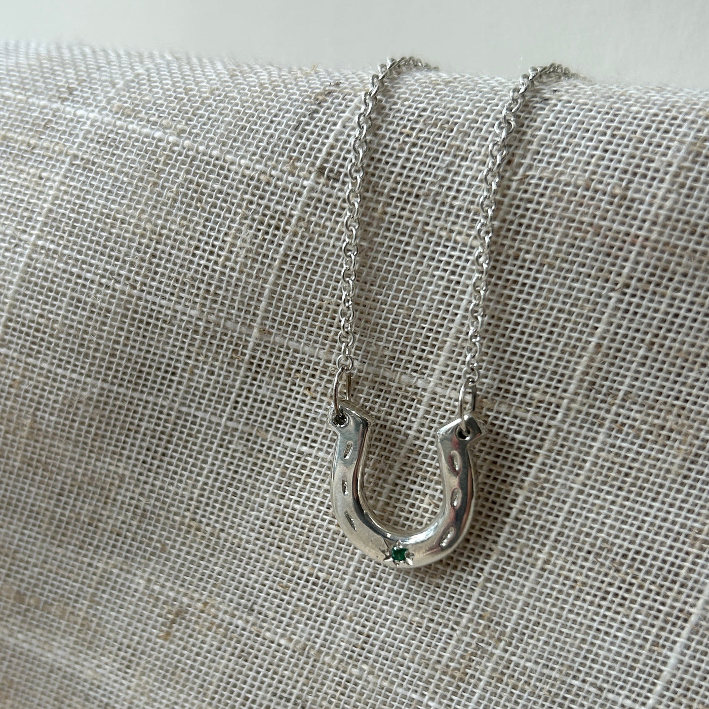 Silver Horseshoe and sapphire on a textured fabric background