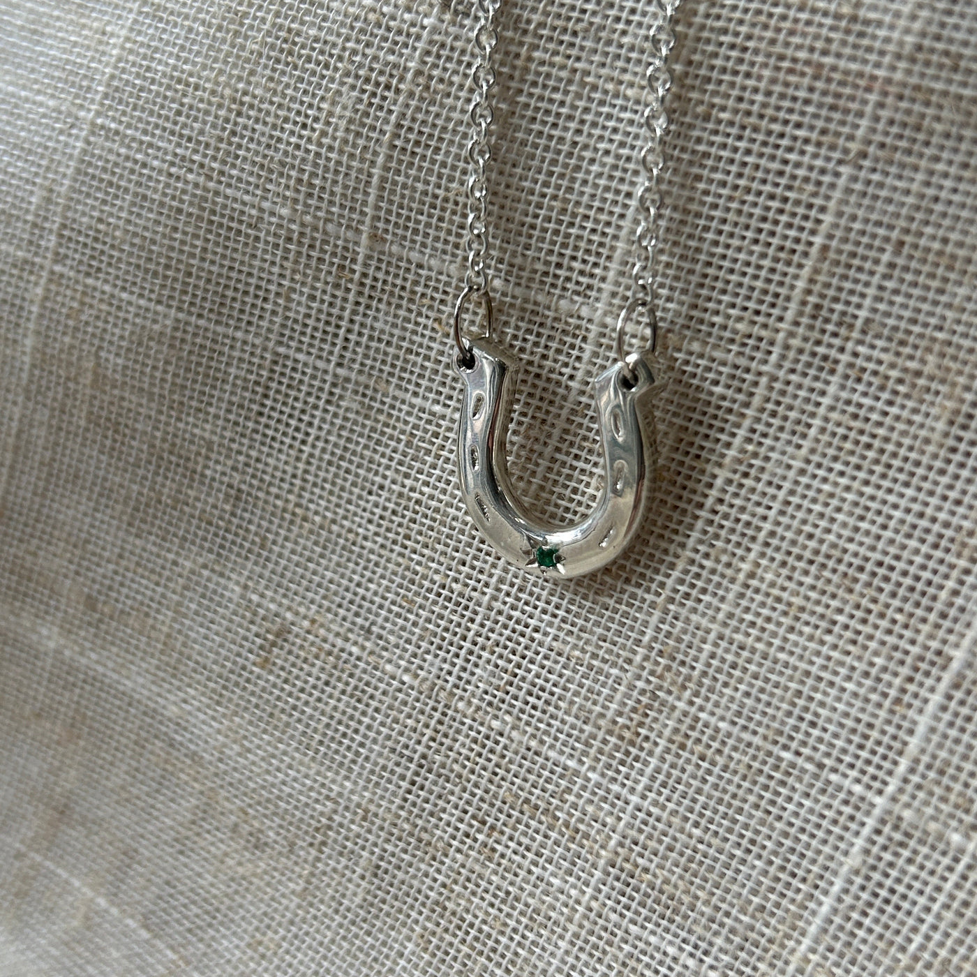 Close-up of a silver necklace clasp on a textured gray fabric background