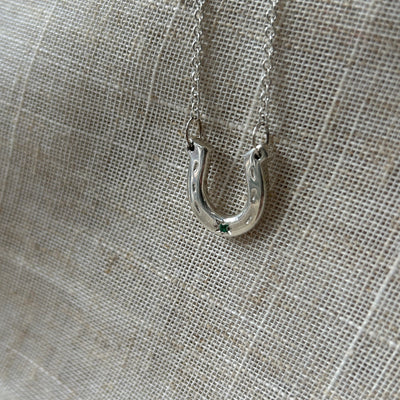 Close-up of a silver necklace clasp on a textured gray fabric background