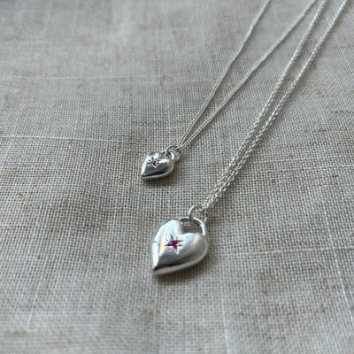 Silver heart-shaped necklace with a star detail on a textured gray surface