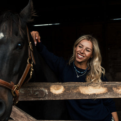 Woman petting a horse inside a stable