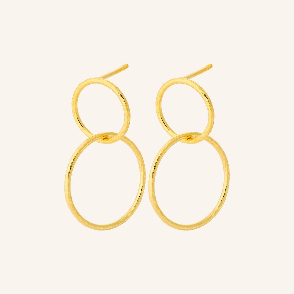 Gold hoop earrings on a light beige background
