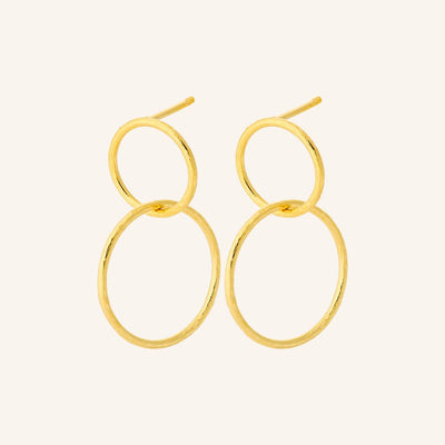 Gold hoop earrings on a light beige background