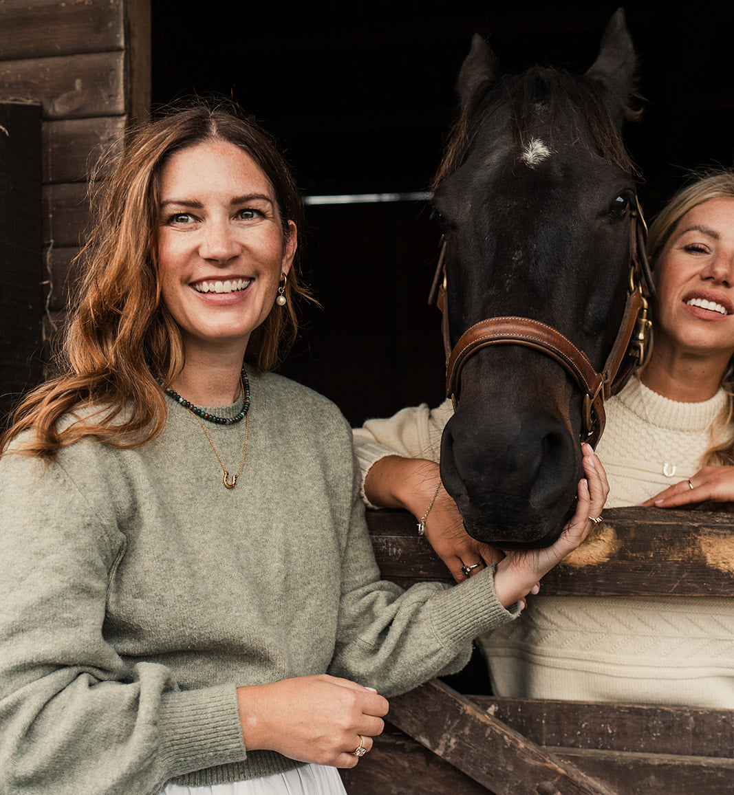 Two women standing next to a horse in a stable