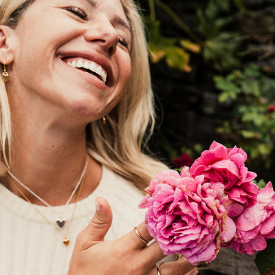 Woman holding pink flowers and smiling outdoors