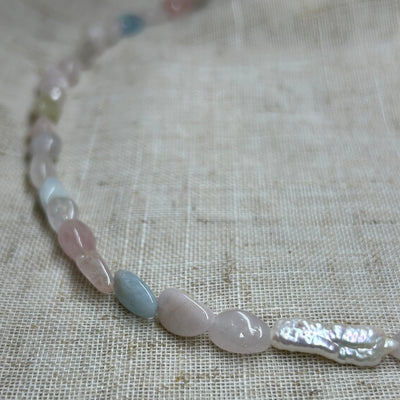 Necklace with light blue and clear beads on a textured fabric background