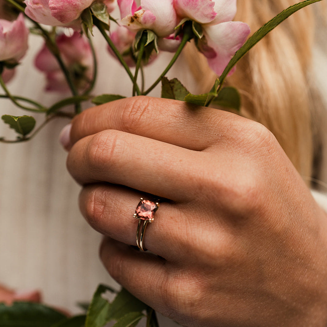 Pink tourmaline ring on woman's hand holding a rose