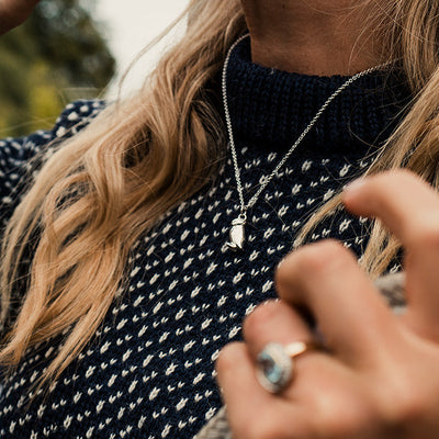 Silver puffin pendant worn by a woman with blonde hair.