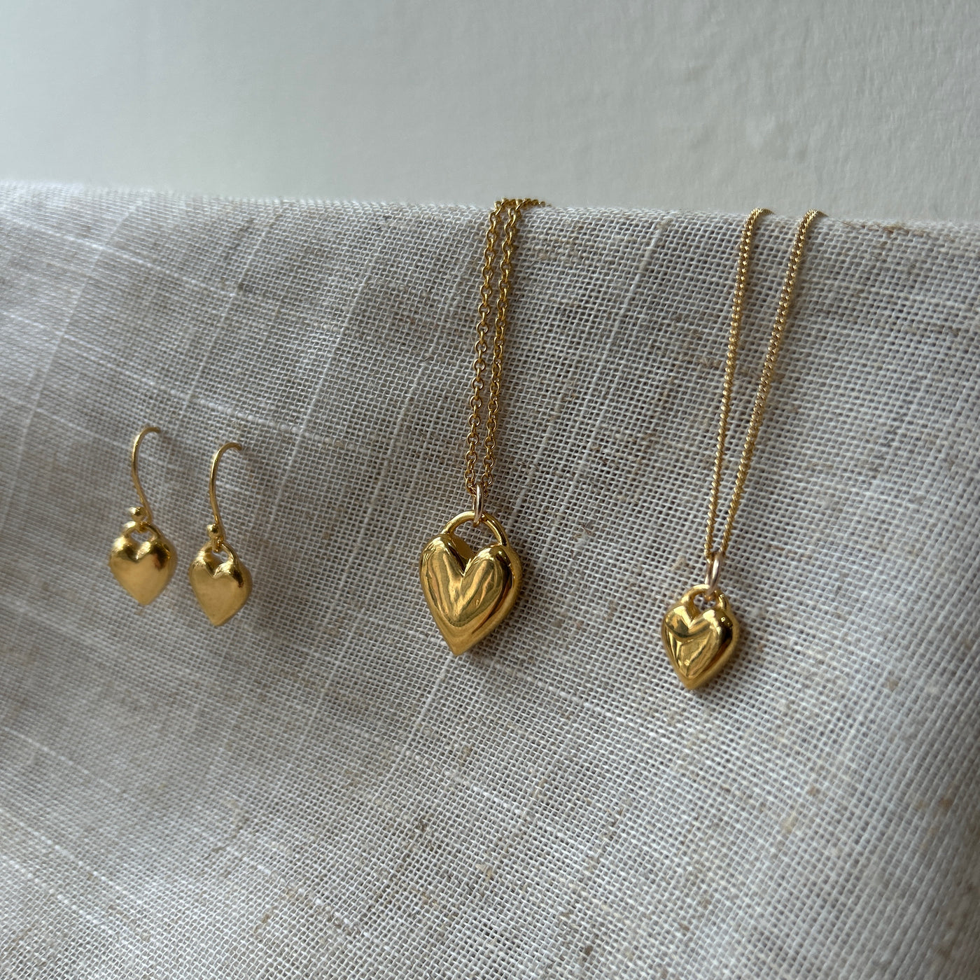 Gold heart-shaped jewelry set on a textured fabric background