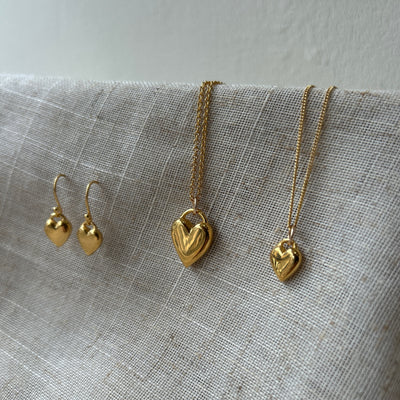 Gold heart-shaped jewelry set on a textured fabric background