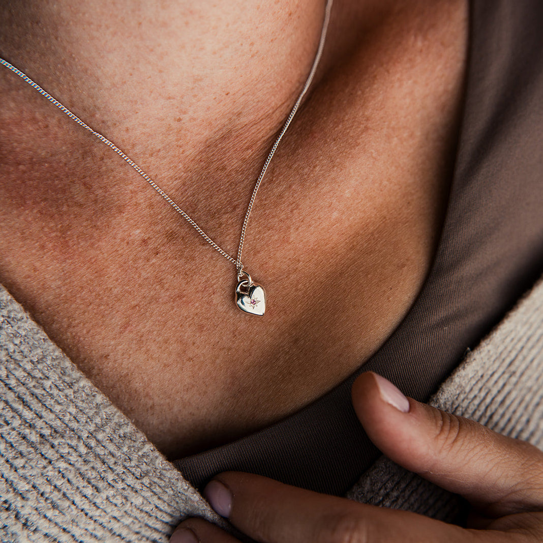 Necklace with a pendant being adjusted on a person's neck.